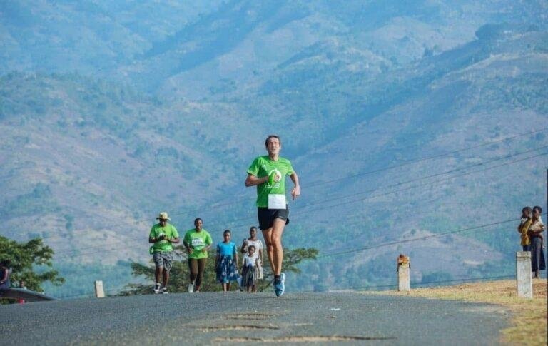 Runners on the road during the Tusker Lite Mt. Rwenzori Marathon, with the Rwenzori foothills in the background